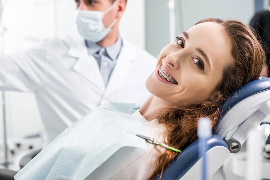 Patient with dental braces smiling in dental chair during orthodontic exam