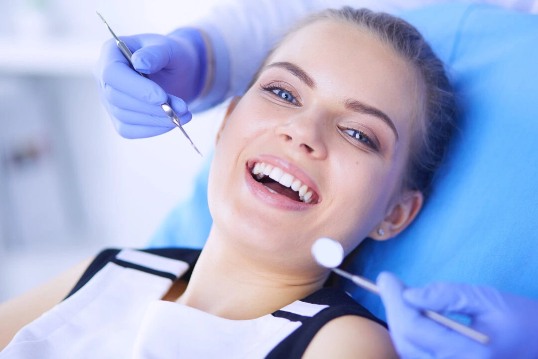Dental hygienist performing professional teeth cleaning on smiling patient