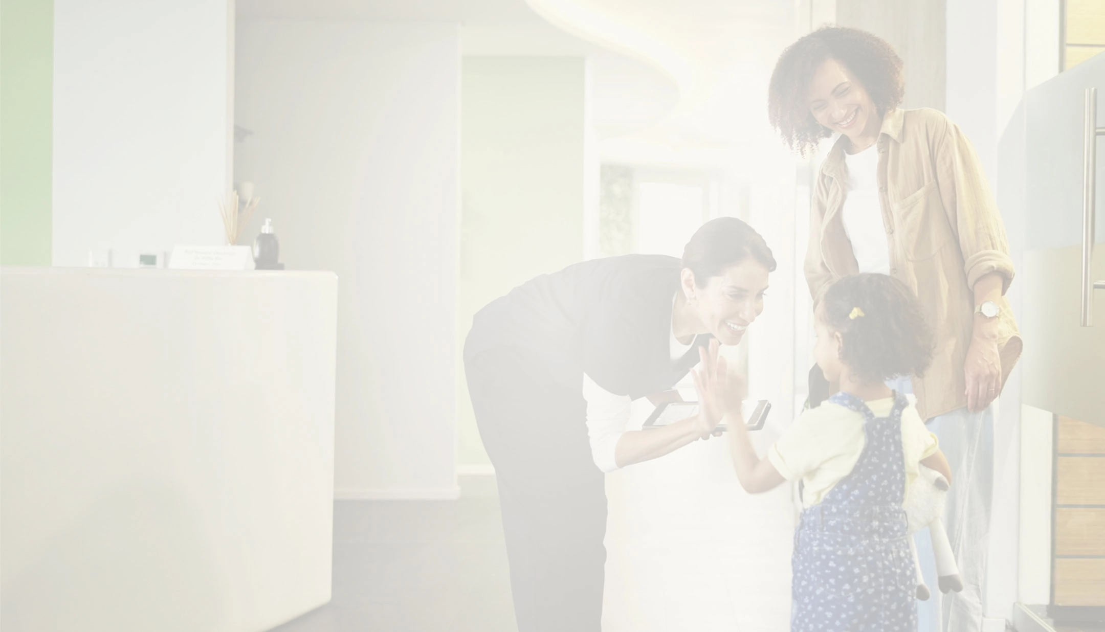 Dental receptionist greeting family with child in bright clinic waiting area